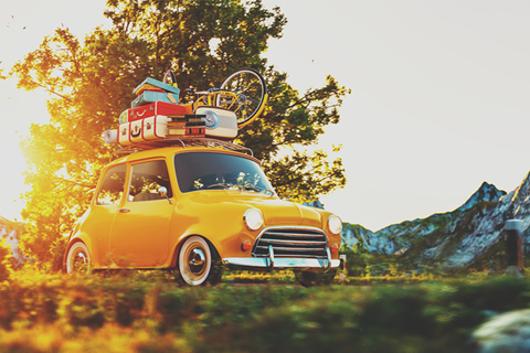 A little yellow car with a lot of luggage and a bike on top of it.